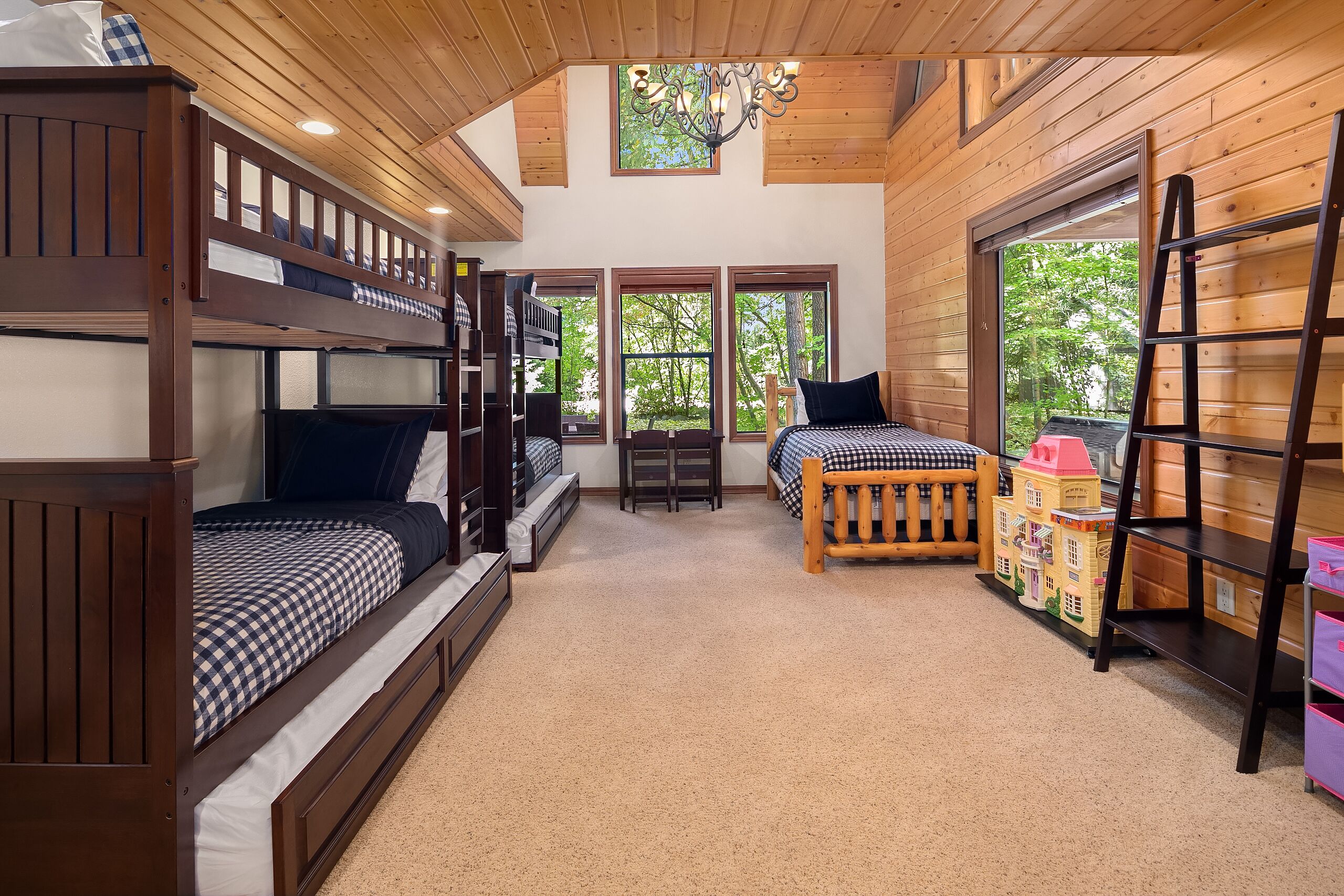 A cozy room with bunk beds, a small table, and a window overlooking greenery.