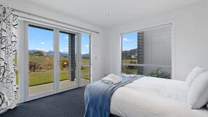 A bedroom with a bed, a large window, and a view of a mountainous landscape.