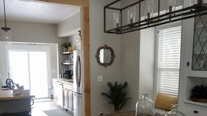 Une cuisine moderne avec un banc en bois, un luminaire suspendu et une vue sur la salle à manger adjacente.