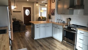 Une cuisine moderne avec un plancher en bois, des appareils électroménagers en acier inoxydable et un îlot central.