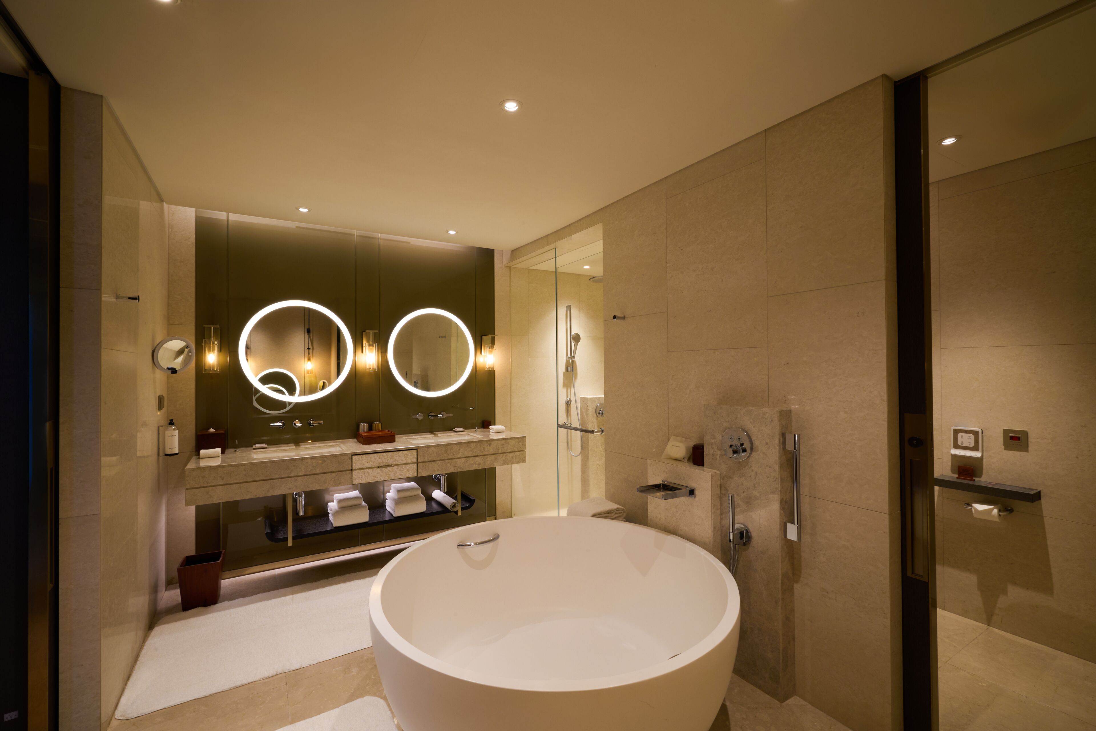 Un baño moderno con una bañera independiente grande, una ducha con cerramiento de vidrio y un tocador con espejo e iluminación.