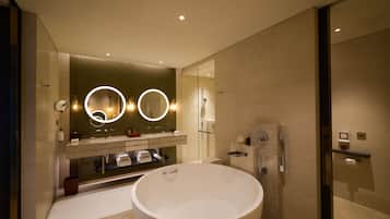 Un baño moderno con una bañera independiente grande, una ducha con cerramiento de vidrio y un tocador con espejo e iluminación.