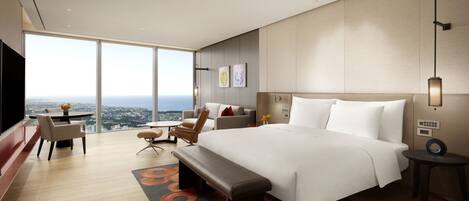 Una habitación de hotel moderna con una cama grande, un área de descanso con vistas y una mesa de comedor.