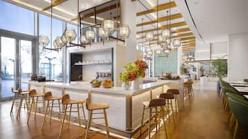 A modern bar area with a central island, bar stools, and pendant lighting.