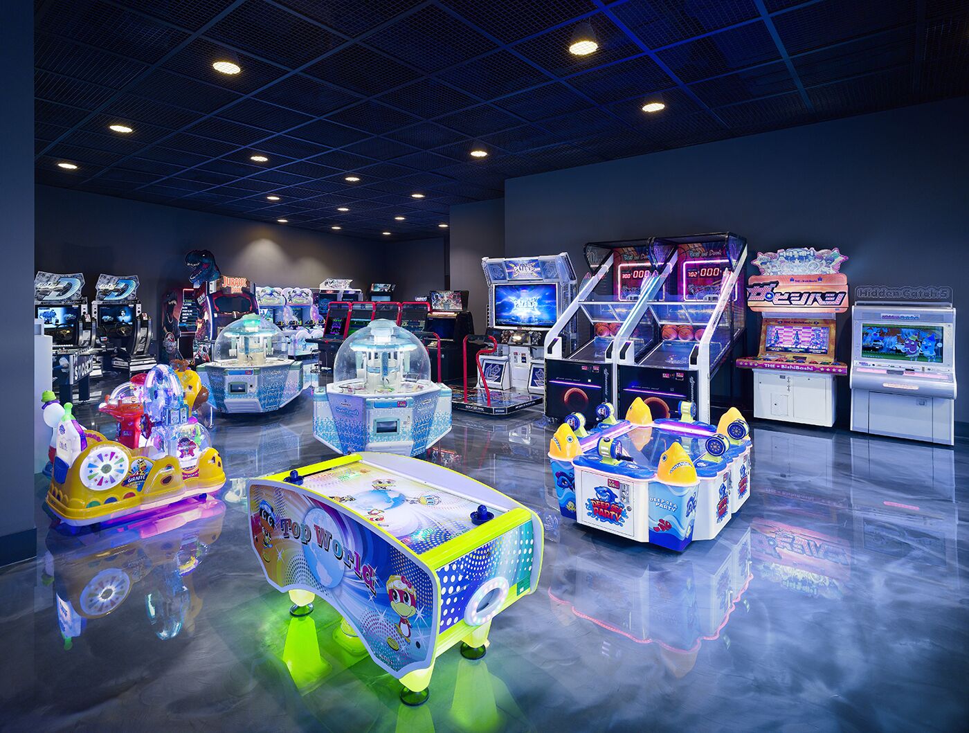 An arcade with various gaming machines, including a prominent 'Top of the World' ride and multiple basketball-themed games.