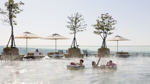 A hot spring area with lounge chairs and umbrellas, surrounded by trees. - Grand Hyatt Jeju (Jeju City)