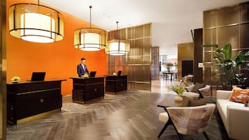 Un vestíbulo de hotel con una recepción, zona de estar y decoración moderna.