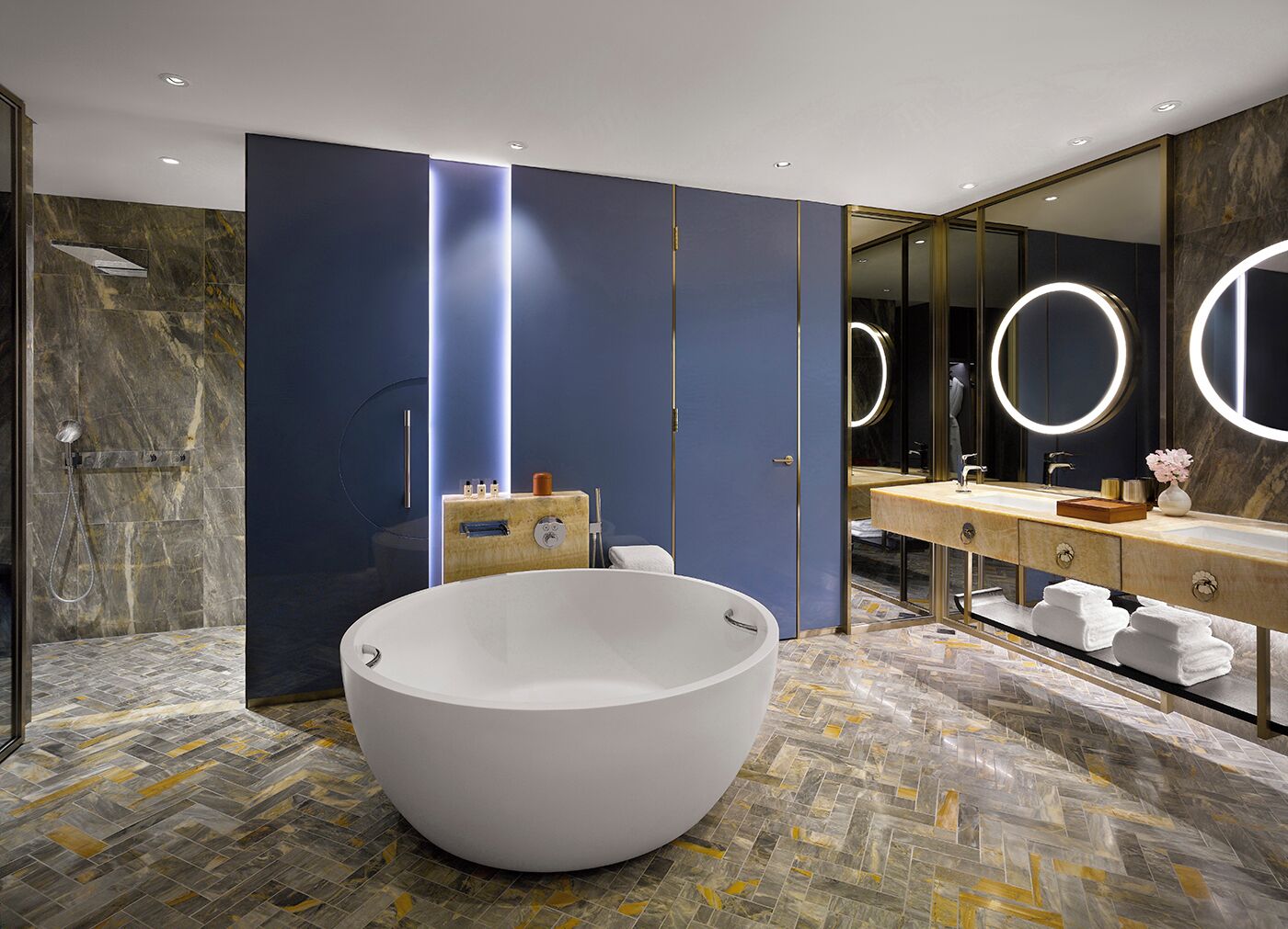 A modern bathroom with a large white bathtub, a vanity with a mirror, and a shower area.
