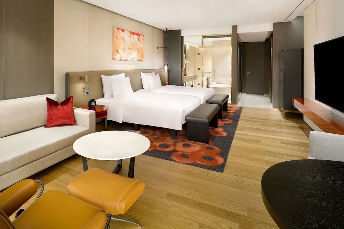 A hotel room with a bed, a sofa, a coffee table, and a TV.