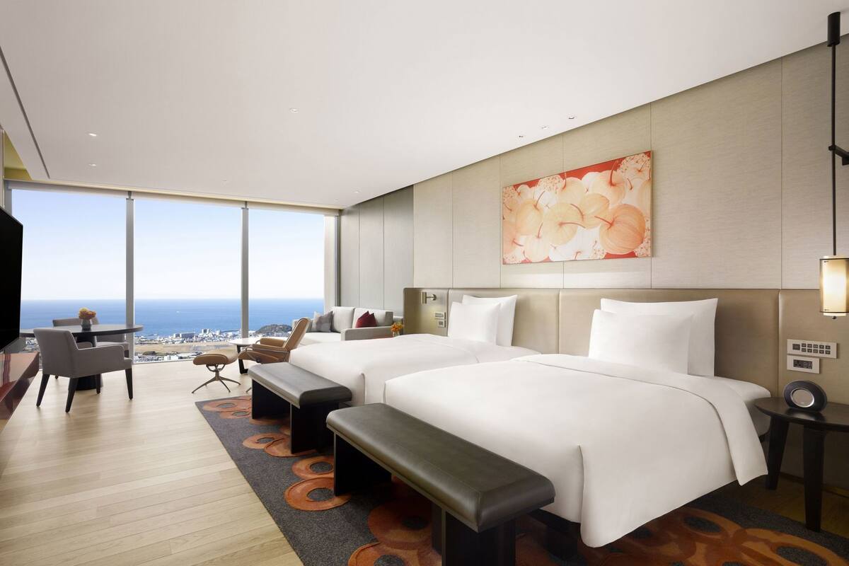 Ein modernes Hotelzimmer mit einem großen Bett, einem Schreibtisch und Blick auf den Ozean.
