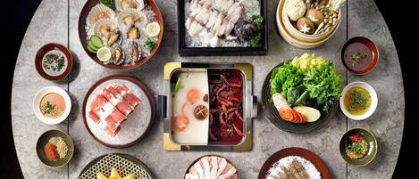 A variety of Japanese dishes including sashimi, seafood, and vegetables arranged on a marble table.