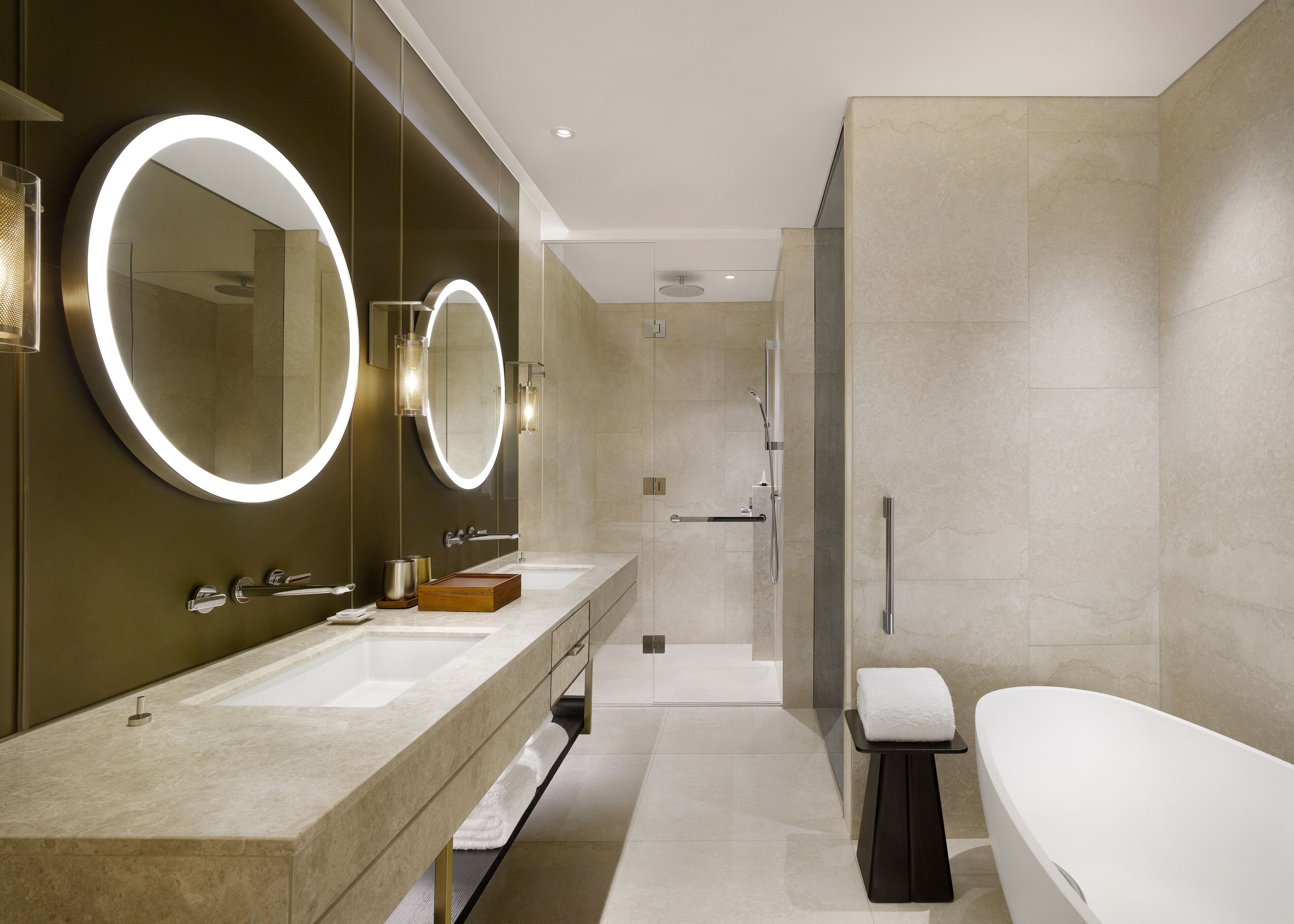 Un bagno moderno con due lavandini, un ampio specchio illuminato, una vasca e uno spazio doccia.