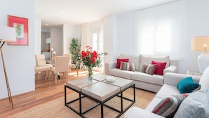 Un salon moderne avec un canapé, une table basse et des fauteuils. On y trouve également un coin repas avec une table et des chaises.