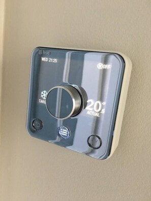 A thermostat with a digital display indicating the temperature as 20 degrees. - Lovely 2- Bed Apartment in Hawick (Hawick)