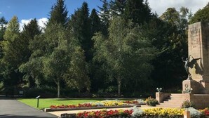 A memorial with a statue, surrounded by a well-maintained garden with colorful flowers and a bench. - Lovely 2- Bed Apartment in Hawick (Hawick)