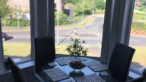 A dining area with a round table, four chairs, and a central plant. - Lovely 2- Bed Apartment in Hawick (Hawick)