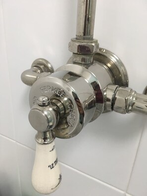 A chrome faucet with a white handle, attached to a white tiled wall. - Lovely 2- Bed Apartment in Hawick (Hawick)