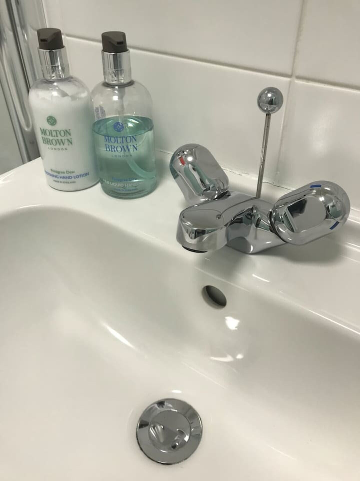 Un lavabo de salle de bain avec deux flacons de lotion pour les mains et un robinet chromé.