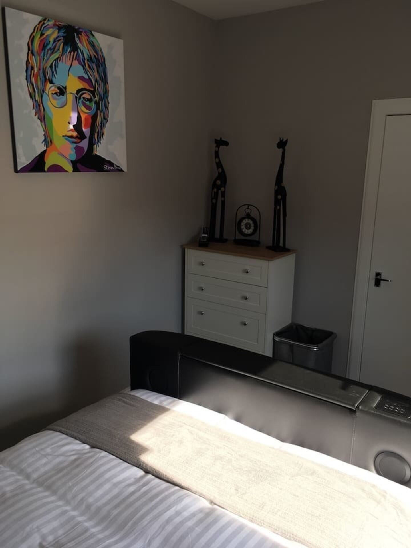 A bedroom with a bed, a dresser, a mirror, and a painting on the wall.