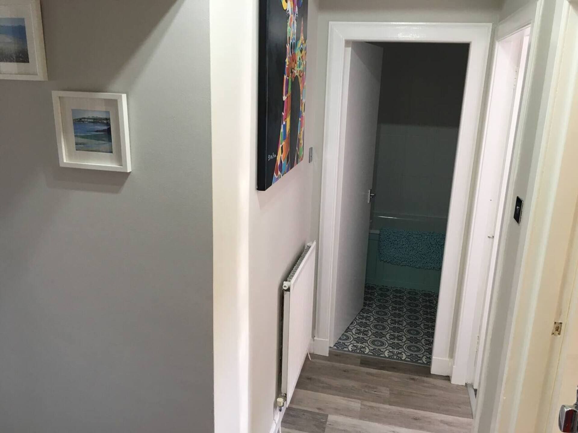 Ein Flur mit einer Treppe, die zu einem Raum mit gemustertem Boden führt.