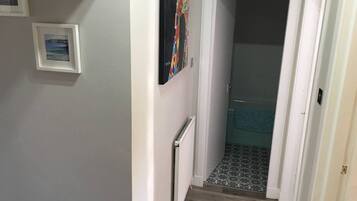 Ein Flur mit einer Treppe, die zu einem Raum mit gemustertem Boden führt.