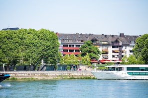 Une rivière sur laquelle navigue un bateau appelé « Emerald Sky », ainsi qu’une rangée d’immeubles dotés de balcons et de fenêtres.