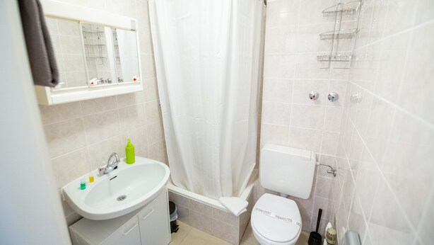 A bathroom with a white sink, toilet, and shower curtain. - City Apartments Rheinterrassen (Koblenz)