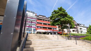 Un hotel con varios pisos, asientos al aire libre y una escalera que lleva a la entrada.