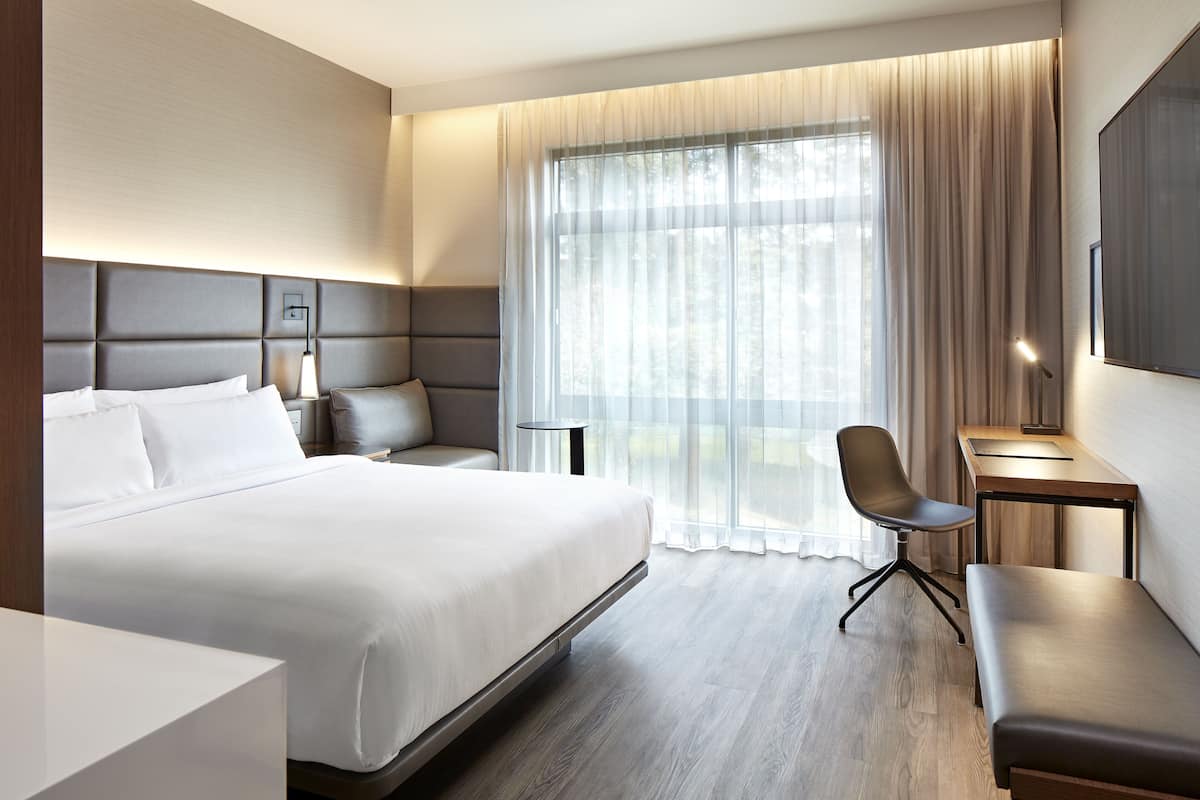 Ein modernes Hotelzimmer mit einem großen Bett, einem Schreibtisch, einem Sessel und einer Bank.