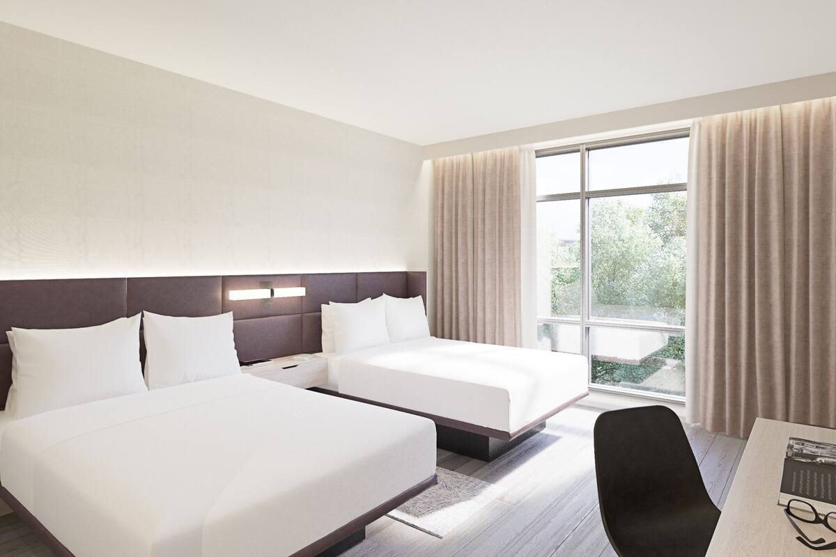 Ein Hotelzimmer mit zwei Betten, einem Schreibtisch und einem Stuhl.