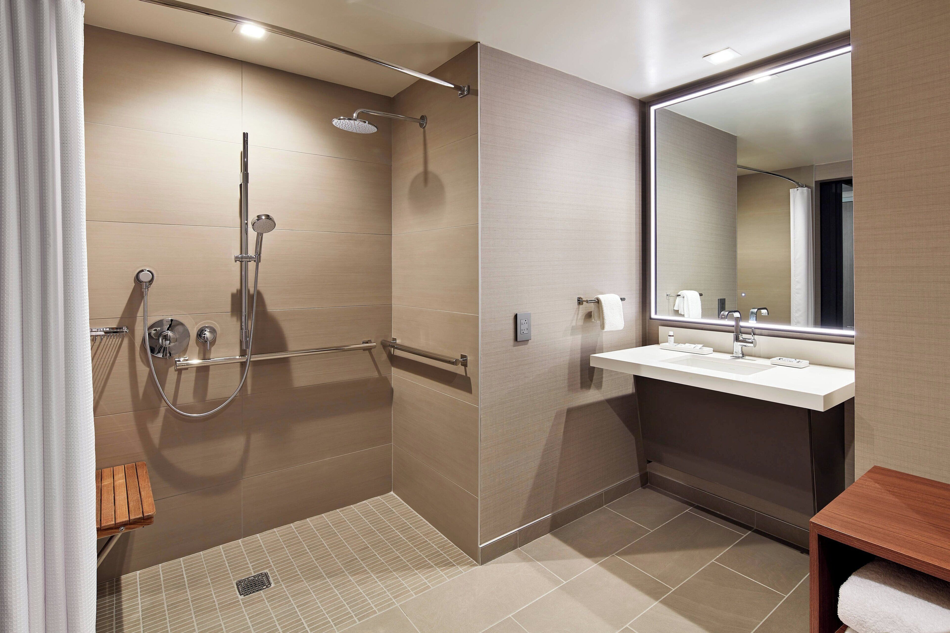 Un baño moderno con cabina de ducha, lavamanos y espejo.
