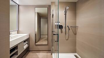 Un bagno moderno con doccia vetrata, uno specchio grande e un mobile contenitore in legno.