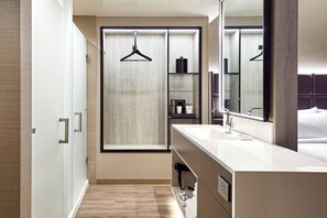 A modern hotel bathroom with a walk-in shower, a large mirror, and a vanity with a sink. - AC Hotel by Marriott Palo Alto (Palo Alto)