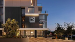 A modern hotel with a flat roof, large windows, and a well-lit entrance.