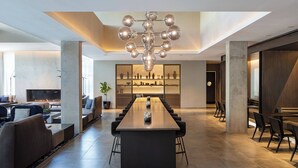 A modern interior with a long dining table, sofas, and a fireplace.