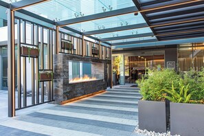 A modern hotel lobby with a glass ceiling, a fireplace, and a seating area with plants. - AC Hotel by Marriott Palo Alto (Palo Alto)