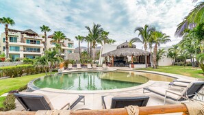 Ein Resort mit Poolbereich, Liegestühlen und einer Struktur mit Reetdach.