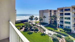 Un hotel frente a la playa con varios balcones, una zona de piscina y vistas al océano.