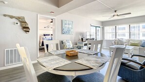 Amplia sala de estar con una mesa de comedor redonda, sillas blancas y un sofá azul.