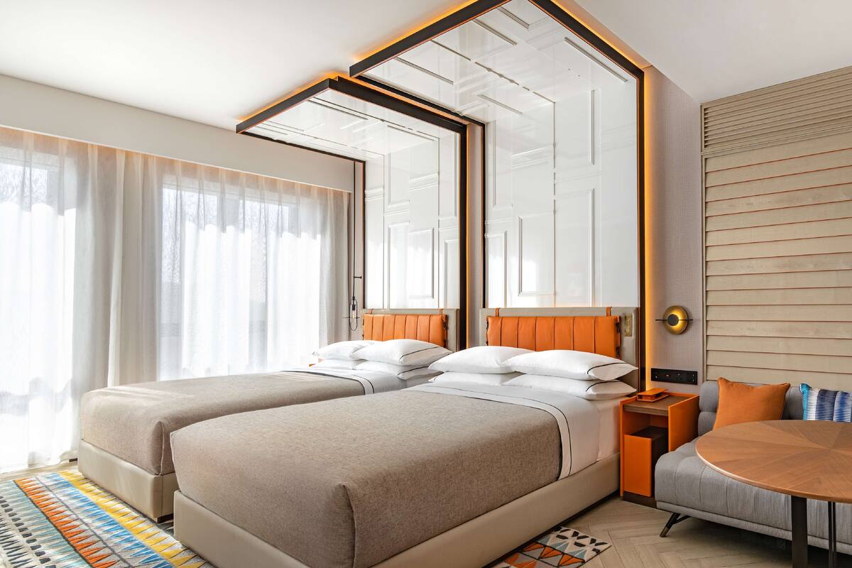 Una habitación de hotel con dos camas, un sofá, una mesita y un espejo grande.