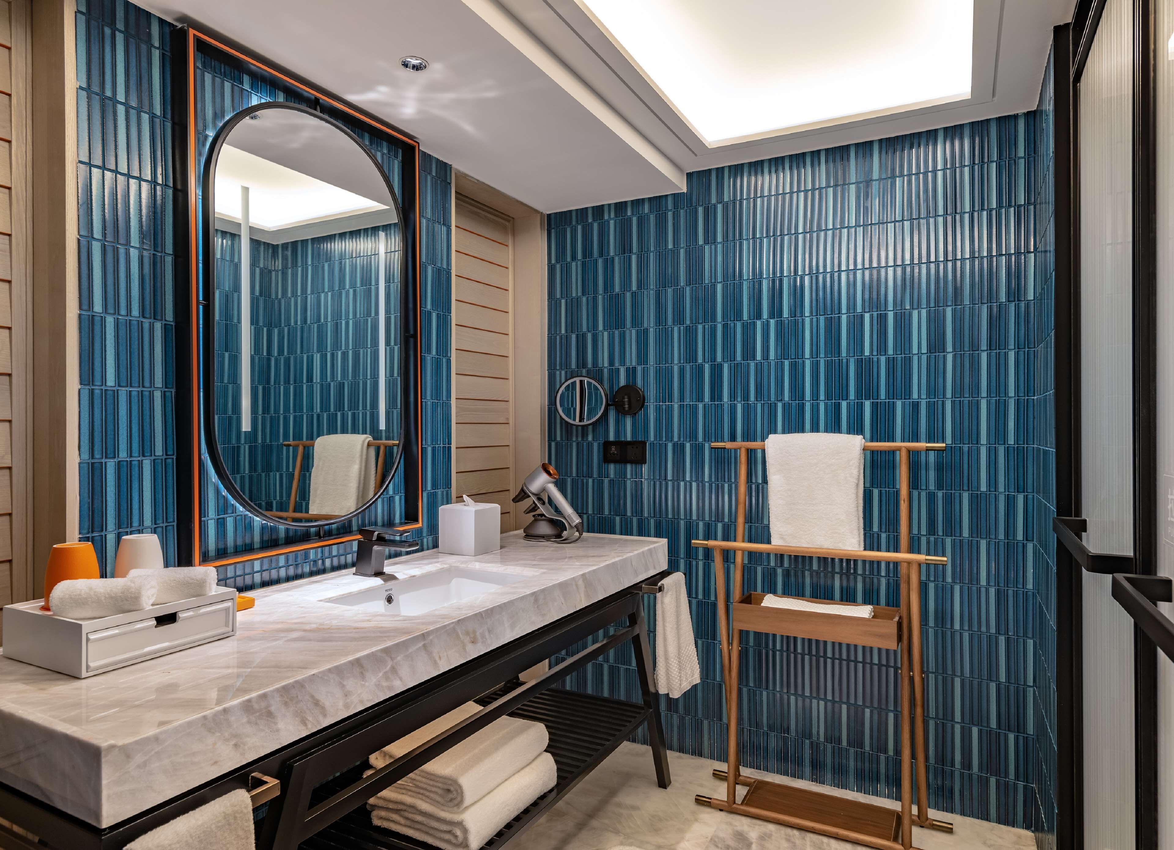 A modern bathroom with a large mirror, a sink, and a towel rack.