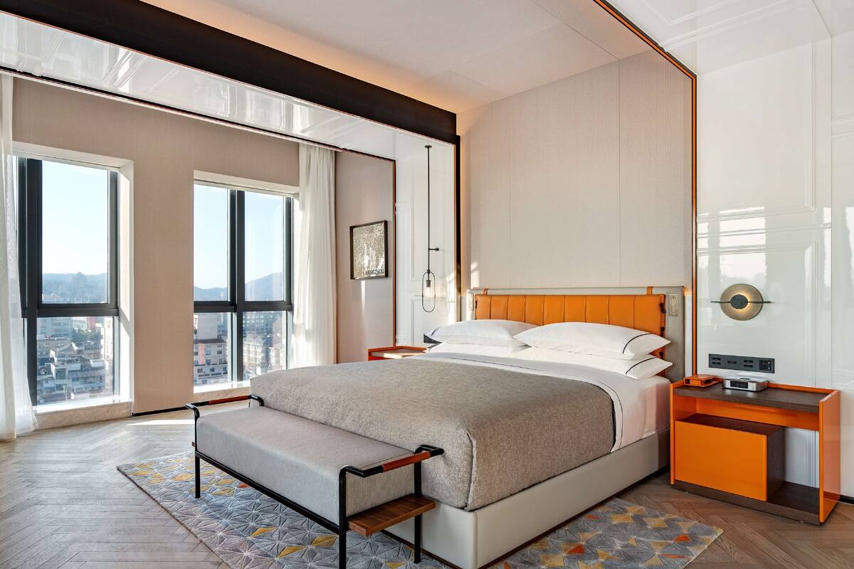 Un dormitorio moderno con una cama grande, una mesita de noche y una mesita auxiliar.