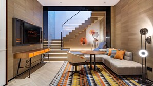 Un salon moderne comprenant un canapé, une table basse, un téléviseur et un escalier menant à un niveau supérieur.