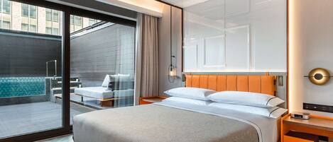 Habitación de hotel moderna con una cama grande, un pequeño rincón de descanso con vistas al exterior y un balcón privado.