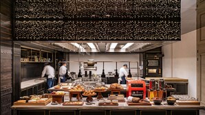 Une cuisine professionnelle où des chefs préparent des plats, un buffet proposant divers mets et une machine à café.