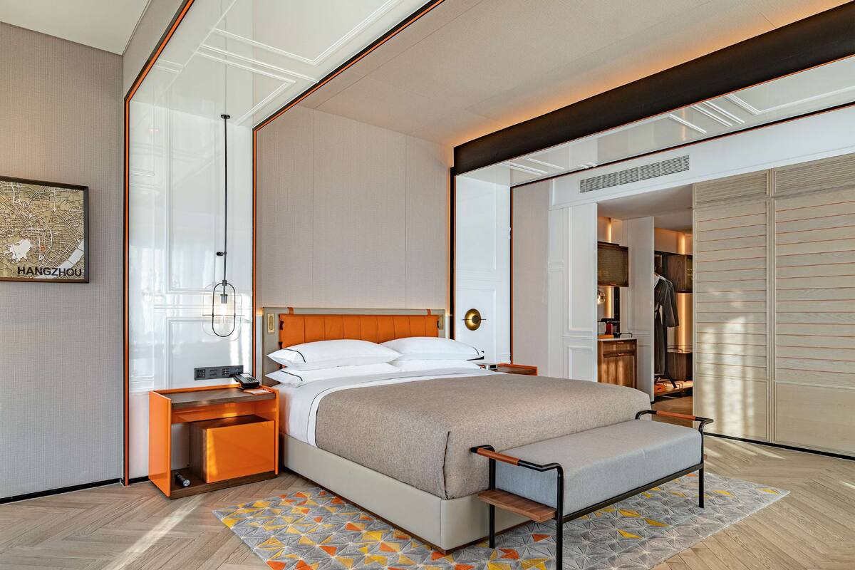 Una habitación de hotel moderna con una cama grande, una mesita de noche, un armario y vistas a la ciudad.