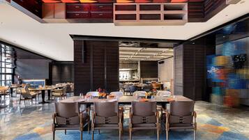A modern dining area with high tables, chairs, and a patterned ceiling.