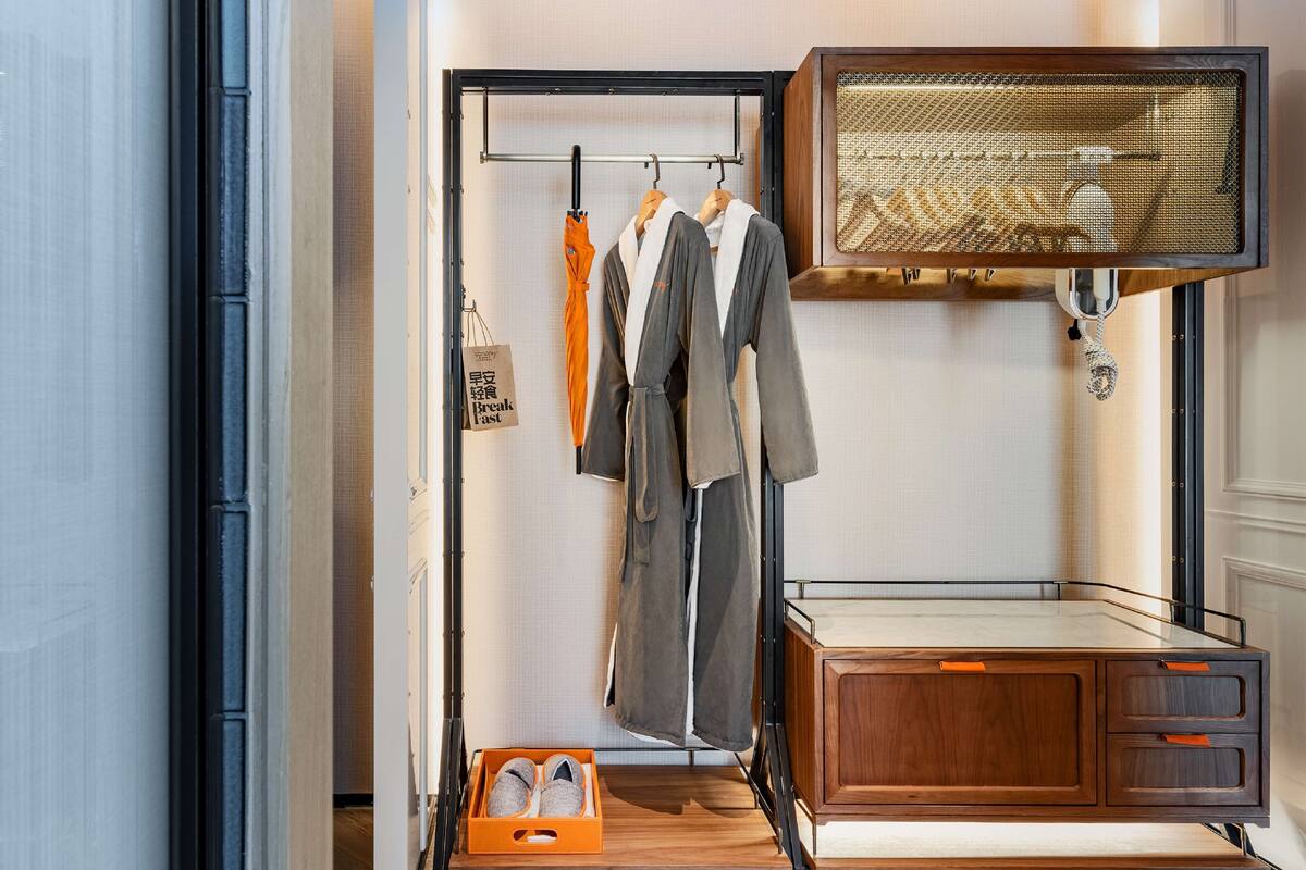 Una habitación moderna con un armario de madera, un perchero con ropa y un zapatero.