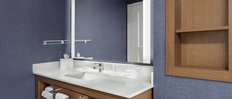 A bathroom with a wooden vanity, a white sink, and a large mirror.