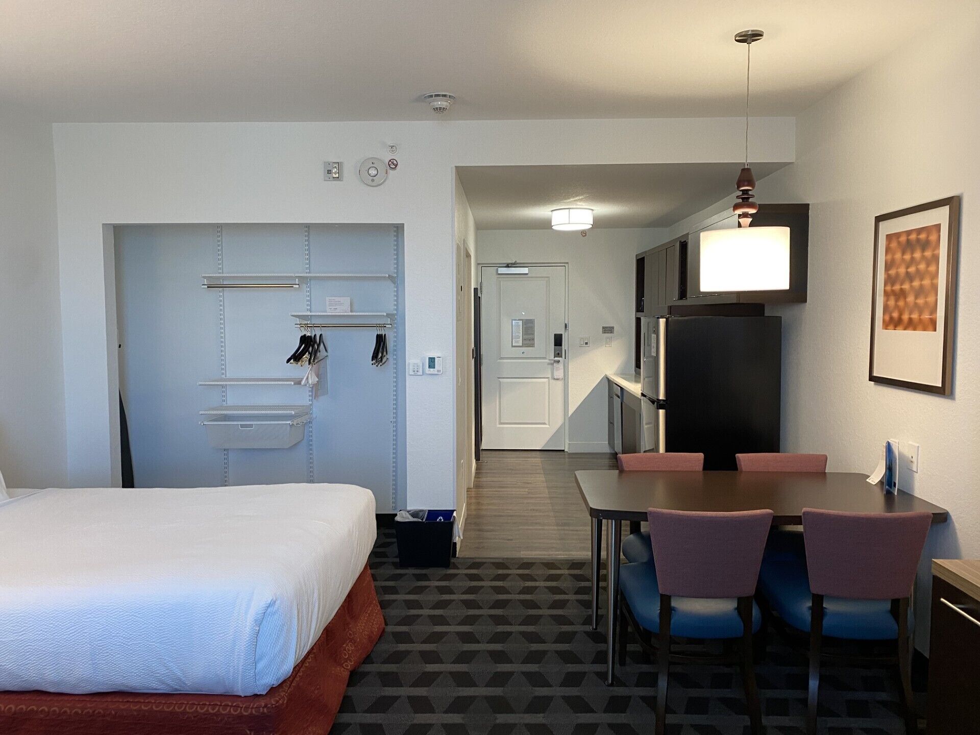 Una habitación de hotel con una cama, un comedor con sillas, un refrigerador y una kitchenette.